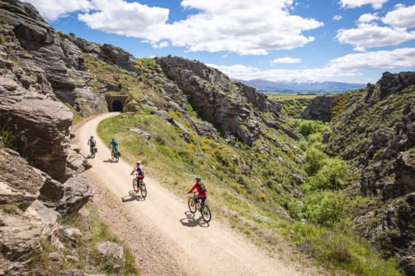 Cyclists on the Central Otago Rail Trail with mountains in the distance